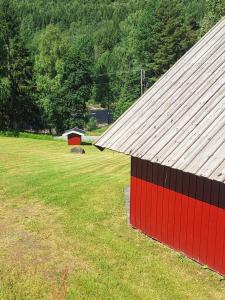a red and black barn in a field at Brufoss Hytte og Laksesenter in Svarstad