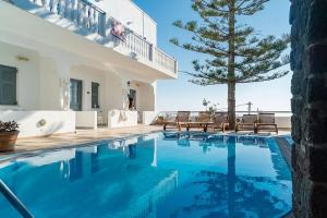 a large swimming pool in a house with a tree at Grande Murano in Fira