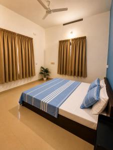 a bedroom with a large bed with blue sheets at Aurena Stays Varkala in Varkala