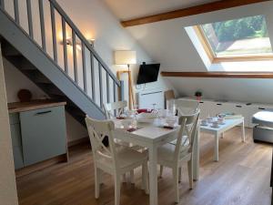 a dining room with a white table and chairs at 2 chambres avec mezzanine in Le Lioran