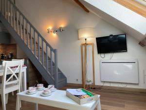 a living room with a white table and a tv at 2 chambres avec mezzanine in Le Lioran