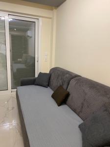 a gray couch in a living room with a window at Apartman Velickovic in Paralia Katerinis