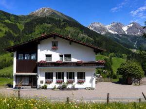 a white house in front of a mountain at Apartmenthaus Ahorn in Mittelberg