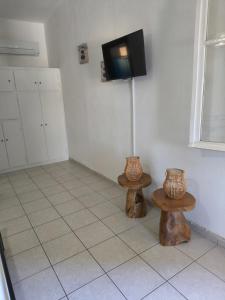 Ein Zimmer mit zwei Tischen und einem Fernseher an der Wand. in der Unterkunft Villa Orizontes in Spetses