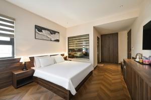 a bedroom with a large white bed and a television at Khách sạn Neva in Long An