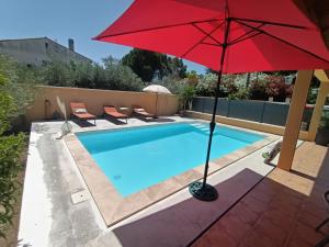 a red umbrella next to a swimming pool at Chambre 2 personnes in Saint-André-de-Sangonis