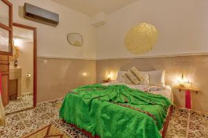 a bedroom with a bed with a green blanket on it at Riad Samir Oasis And Spa in Marrakesh