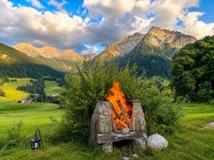 a fire pit in a field with mountains in the background at Apartmenthaus Ahorn in Mittelberg