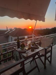 a table with wine glasses on a balcony with a sunset at Navarino Golden sunset Apartment in Pylos