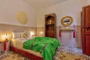 a bedroom with a bed with a green blanket on it at Riad Samir Oasis And Spa in Marrakesh