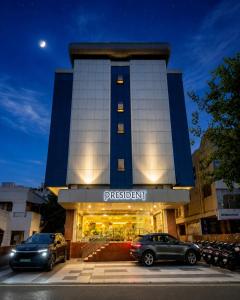 a building with two cars parked in front of it at Hotel President, Pure Veg in Indore