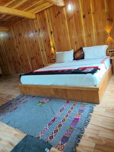 ein Bett in einem Holzzimmer mit einem Teppich in der Unterkunft Him cottage in Gushaini + 18 Fotos