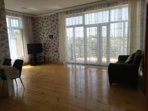 a living room with large windows and a wooden floor at TamoLand in Astara
