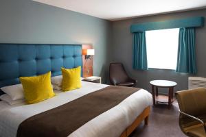 a bedroom with a large bed with yellow pillows at Best Western Atlantic Hotel in Chelmsford