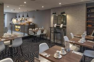 a restaurant with wooden tables and white chairs at Best Western Plus Delmere Hotel in London