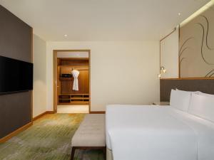 a bedroom with a large white bed and a closet at Radisson Golf & Convention Center Batam in Batam Center