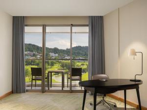a room with a desk and a table with chairs at Radisson Golf & Convention Center Batam in Batam Center +109 photos