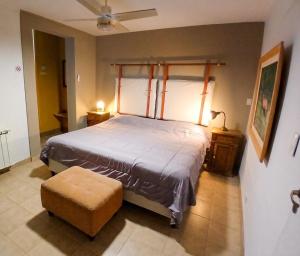 ein Schlafzimmer mit einem Bett und einem Hocker in einem Zimmer in der Unterkunft PATO BLANCO in Ciudad Lujan de Cuyo