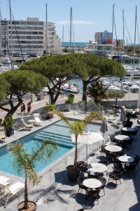 ein Pool mit Tischen und Stühlen neben einem Yachthafen in der Unterkunft The Originals Boutique, Hôtel Neptune, Montpellier Sud in Carnon-Plage