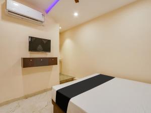 a bedroom with a bed and a tv on the wall at Hotel O BSS INNS in Warangal +21 photos
