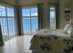 a bedroom with large windows and a bed with a view at Bord Mer House in Glacis