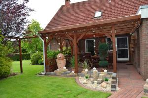 a wooden gazebo in the backyard of a house at Ferienhaus Nikki 35528 in Uplengen