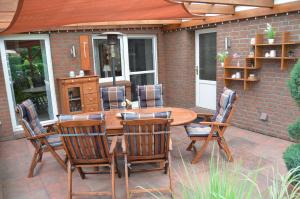 a patio with a wooden table and chairs at Ferienhaus Nikki 35528 in Uplengen +57 photos