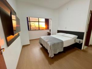 a hotel room with a bed and a window at Hotel Valadares in Alfenas