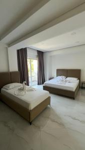 two beds in a large room with a large window at Laska's Rooms Sarandë in Sarandë