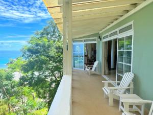 a porch with white chairs and a view of the ocean at Bord Mer House in Glacis