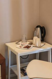 a white table with a tea kettle and a plate on it at Hotel Magllara in Sarandë