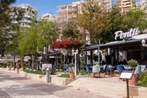 a street in a city with tables and chairs at Hotel Magllara in Sarandë