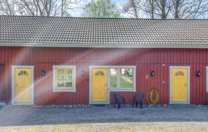 a red building with yellow doors and two chairs at 1 Bedroom Lovely Apartment In Värnamo in Värnamo