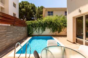 a swimming pool with a table and chairs next to a house at Gaia - 4 Bedroom House in Larnaca in Larnaca