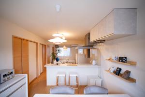 a kitchen with a white counter and stools in it at Shiki Art Hotel Yufu in Yufu