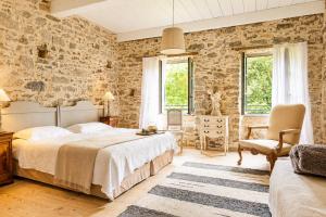 a bedroom with a bed and a stone wall at Domaine de la Salutière - Charme & Confort au cœur du Pays Cathare in Lauraguel