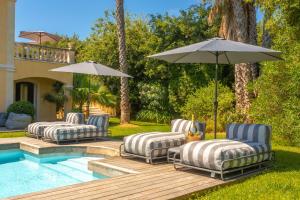 three lounge chairs and an umbrella next to a pool at Villa Seize St Tropez in Saint-Tropez