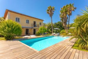 a swimming pool in front of a house with palm trees at Villa Seize St Tropez in Saint-Tropez