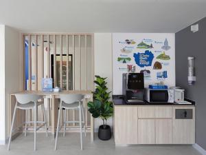 a kitchen with a counter and a table and stools at HOP INN Phetchaburi in Phetchaburi