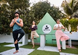 three people doing yoga in front of a green pyramid at Zen Colive in Pune