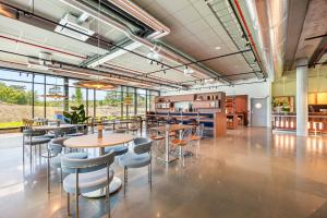 a cafeteria with tables and chairs and windows at Comfort Hotel Grimstad in Grimstad