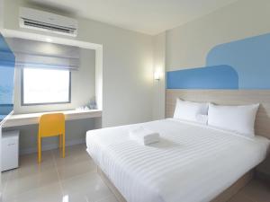 a white bedroom with a bed and a yellow chair at HOP INN Phetchaburi in Phetchaburi +19 photos
