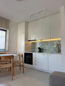 a kitchen with white cabinets and a table and chairs at Stan 11 in Đenovići +2 photos