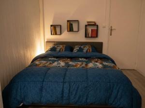a bed with a blue comforter in a bedroom at Beau 2 pièces climatisé, beaux volumes et lumineux - toutes commodités - Lille Gares direct en 30 minutes in Tourcoing