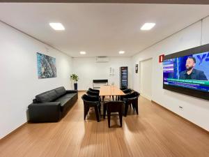 a living room with a couch and a table and a tv at Hotel Valadares in Alfenas