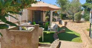 a patio with a table and chairs under an umbrella at Minavita - Vue mer, Plage à pied, Ruppione, Corse in Pietrosella