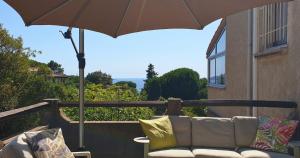 a couch sitting on a porch with an umbrella at Minavita - Vue mer, Plage à pied, Ruppione, Corse in Pietrosella +10 photos
