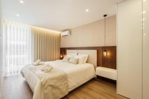 a bedroom with a large white bed and a tub at Seaside Beach Condo by Minho's Guest in Apúlia