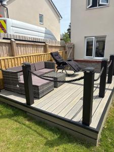 a wooden deck with two chairs and a hammock at 3,Lime Tree Ave in Haverfordwest
