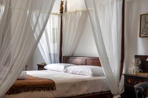 a bedroom with a canopy bed with white curtains at La Dama Stanca in Narni